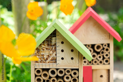 Two insect hotels or bee hotels in a summer garden with flowers. An insect hotel is a manmade structure created to provide shelter for insects in a variety of shapes and sizes and materials.	