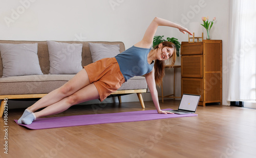 Beautiful Asian woman, she doing exercises on yoga mat, exercises at home, she does squats.
