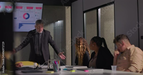 Frustrated manager holding head in hands during tense office meeting as disheartened team reacts to stressful performance review