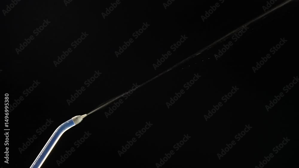 Portable oral irrigator on black background, close up. Dental teeth whitening, flosser bucal tooth cleaner, waterpulse, water thread for teeth. Stream of water from an irrigator nozzle Portable oral irrigator on black background, close up. Dental teeth whitening, flosser bucal tooth cleaner, waterpulse, water thread for teeth. Stream of water from an irrigator nozzle