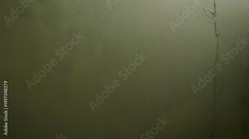 An olive green painted wall exhibits a rough texture with imperfections and a vertical seam creating a visually interesting aged industrial background surface.