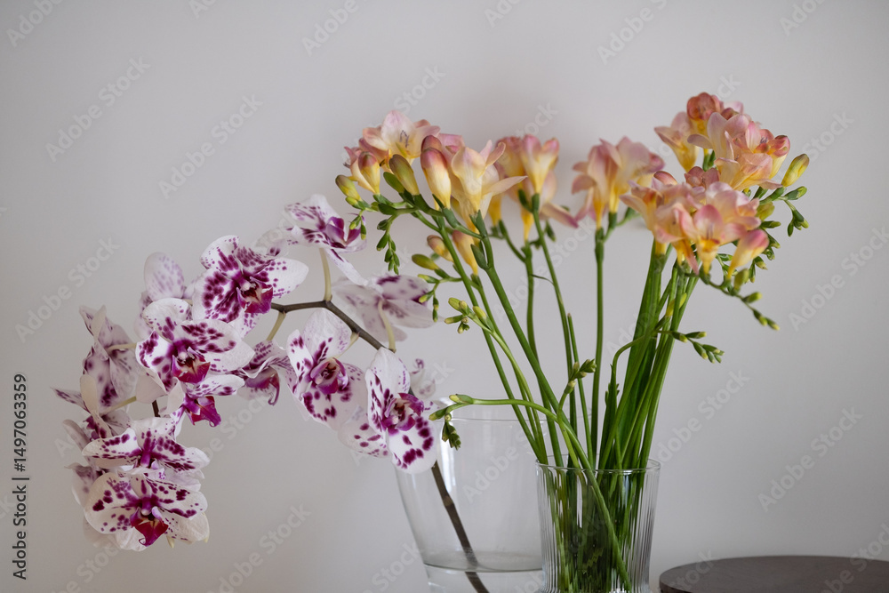 Fototapeta premium Elegant orchid and freesia bouquet in transparent vases