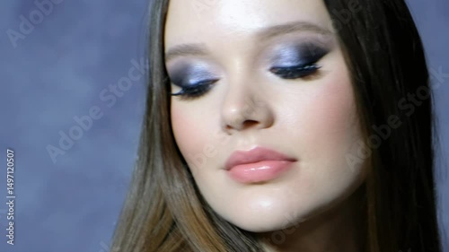 Video of female with earrings in the ear on blue background.