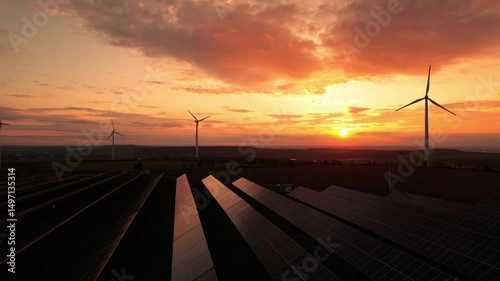 Windmill turbines generating green energy electric.
Aerial view. Green energy reduce carbon emissions and makes earth cleaner and more ecological. Solar panels park and wind turbines at sunset.