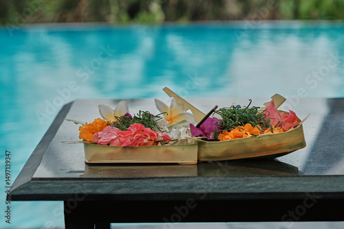 Beautiful offering trays with floral arrangements by the poolside in Bali during a sunny afternoon
