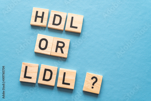 Concept of difference between HDL and LDL cholesterol, with terms composed with wooden alphabet on a blue background; bad cholesterol LDL.

