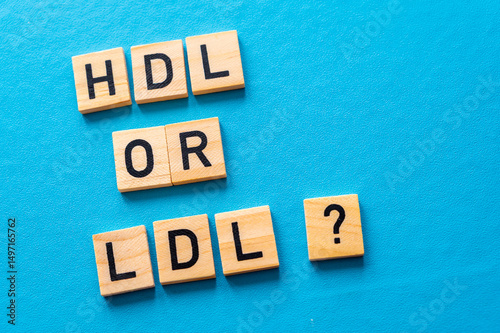 Concept of difference between HDL and LDL cholesterol, with terms composed with wooden alphabet on a blue background; bad cholesterol LDL.
