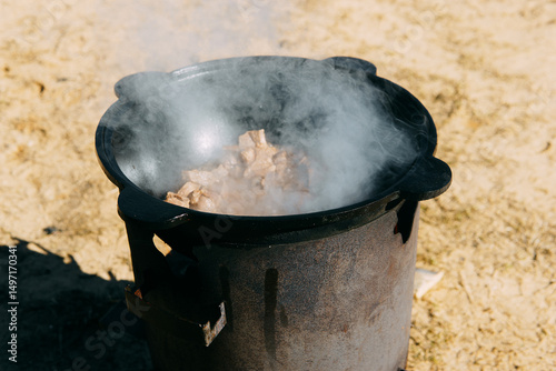 Meat cooking in cauldron outdoor. Plov recipe with meat. Cooking food street. Traditional cuisine and oriental dish.