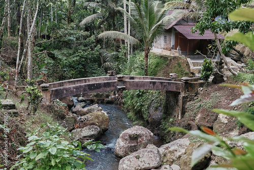 Stone bridge over a serene river in the lush jungle of Bali, Indonesia, surrounded by tropical vegetation