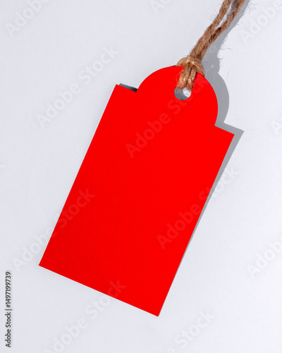 Red Price Tag. Red Empty Cardboard Tag on a White Background. Red Paper Tag With Copy Space.  Discount Label Hanging On a Cord, Ideal For Sale, Promotion. 