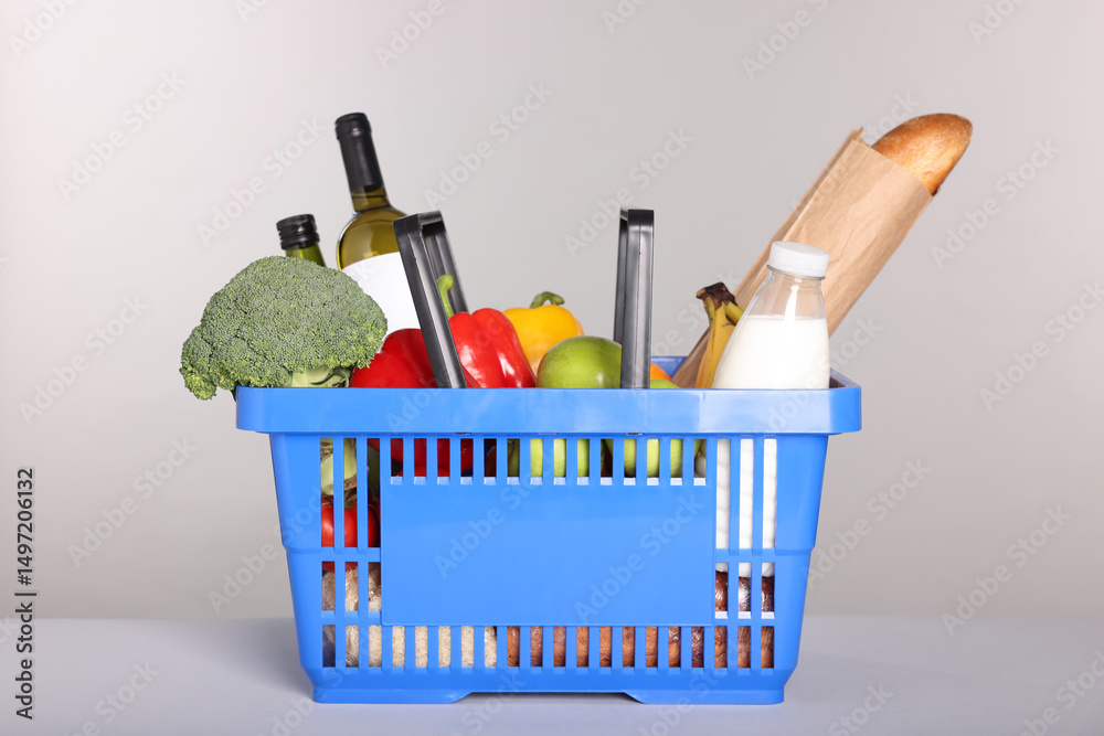 Fototapeta premium Shopping basket with different food products on gray background