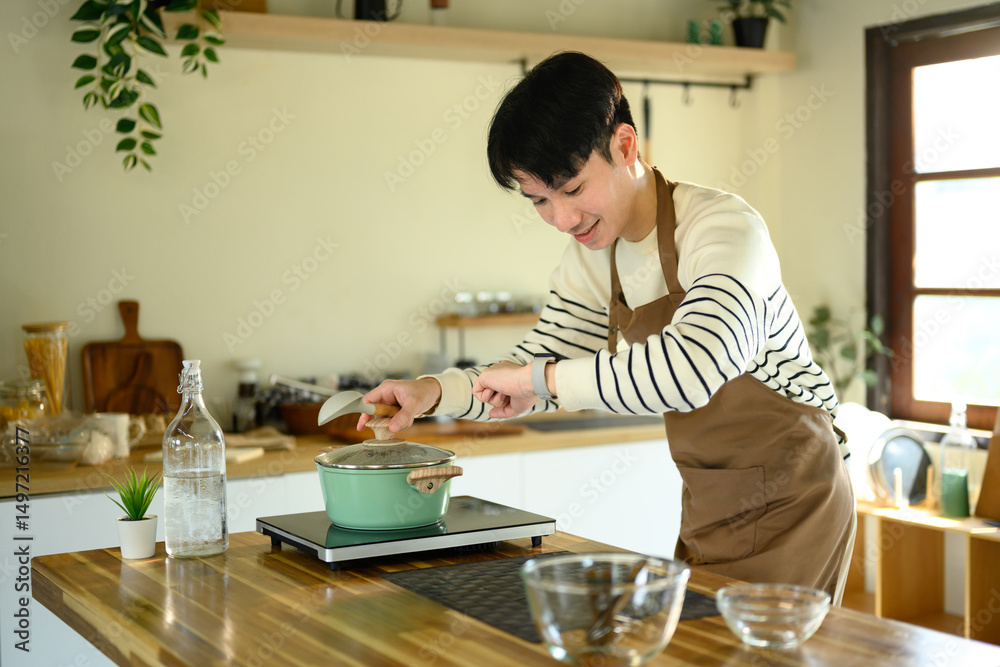 Happy Asian man cooking at home with fresh ingredients Happy Asian man cooking at home with fresh ingredients
