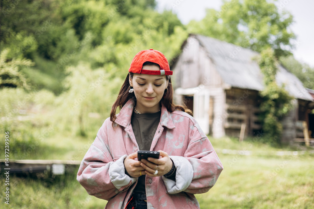 Fototapeta premium Teen girl using smartphone outdoors in countryside, copy space.