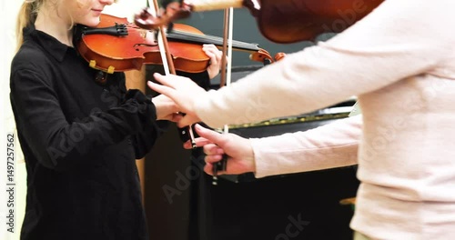girl violinist practicing to vibrate a bow in a music class with a teacher