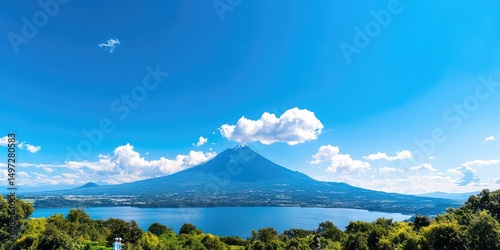 Majestic view of a volcanic mountain overlooking a serene lake under a bright blue sky with clouds