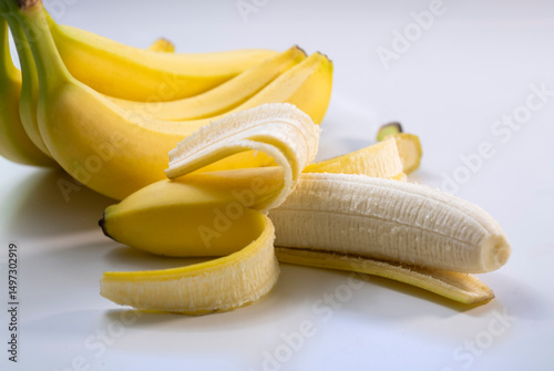 Studio shot of bunch of ripe bananas with one partially peeled