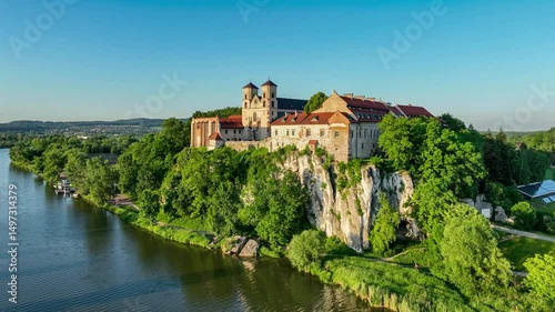 Tyniec near Krakow, Poland. Active Benedictine abbey, monastery and church on the rocky cliff and Vistula River. Aerial 4K video, summer, sunset light. Blue sky with copy space