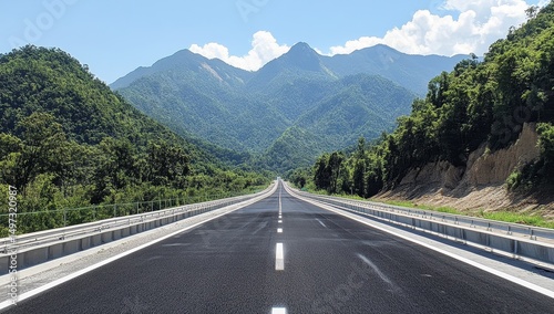 a straight road leads to the mountains, with green trees on both sides
