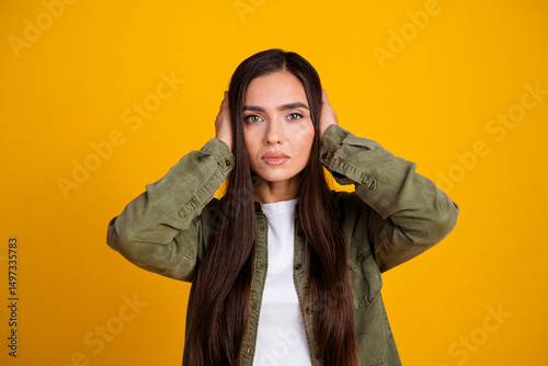 Portrait of a Stylish Young Woman with Long Brunette Hair Posing Against a Bright Yellow Background
