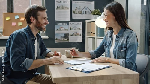 positive realtor and buyer with contract sitting at table in real estate office