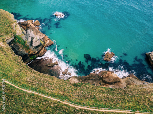 Aerial view of rugged coastline with turquoise water and rocky cliffs.