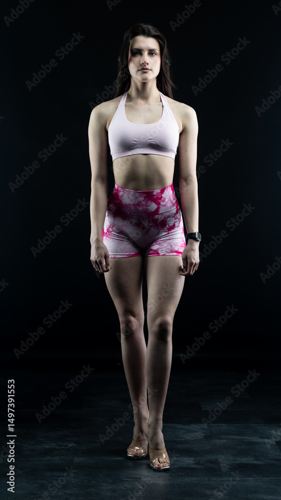 Fototapeta premium Confident fitness model posing on black background showing muscles 