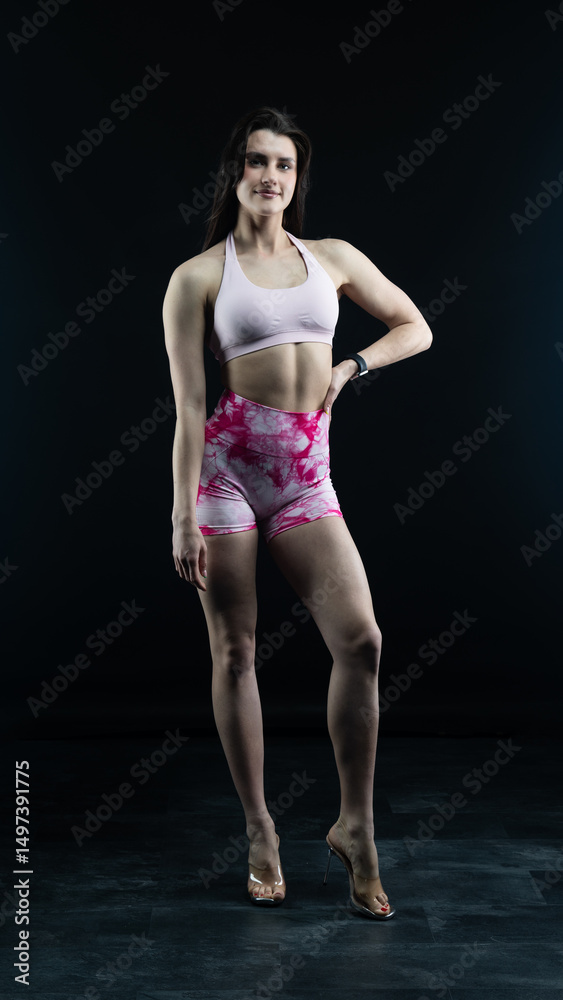 Obraz premium Confident fitness model posing on black background showing muscles 
