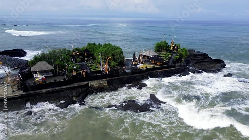 Aerial view of Pura Mengening in Cemangi Beach in Bali, showcasing dramatic rock formations, black sand, ocean waves, and a seaside temple.