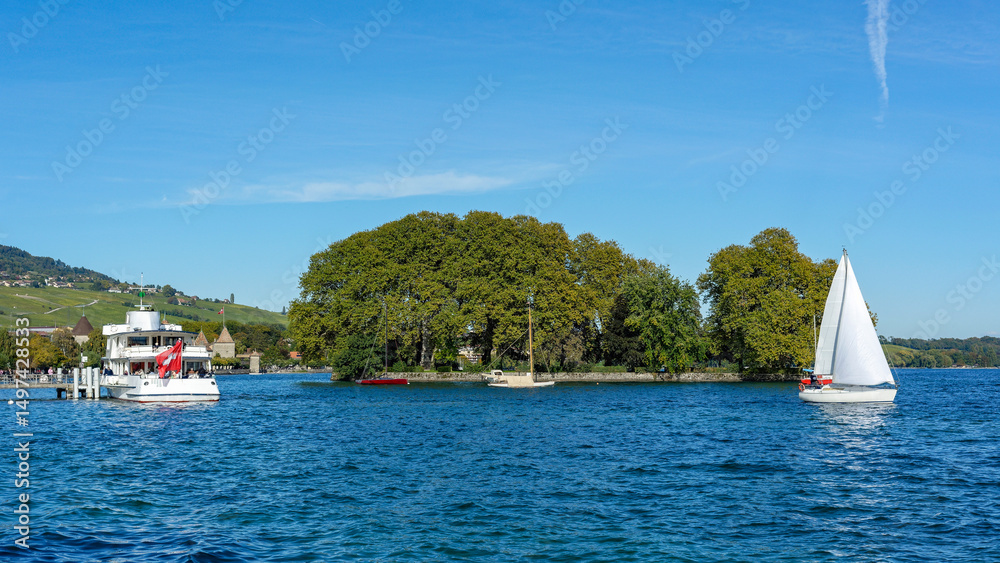 Obraz premium Un voilier et un bateau de croisière sur les rives du lac de Genève à Rolle en Suisse