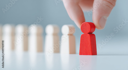One hand selects a red wooden figure, symbolizing talent selection