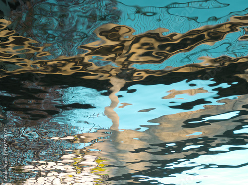 Blue water reflex background. Abstract reflection and abstract inspection elements in water. City, buildings, house elements distorted in the river. Rippled water texture. Disordered water surface.