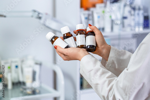 Doctor hold vaccine bottle vial in laboratory. Doctor hand holds the glass drug bottles. Bottle use for pills, supplements, vitamins, capsules. Blank label, woman hands holding bottles