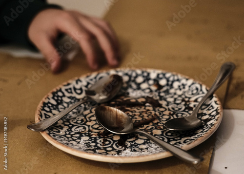a dirty plate of food with cutlery and the hands of a child busy eating the meal in an Italian house during lunch time