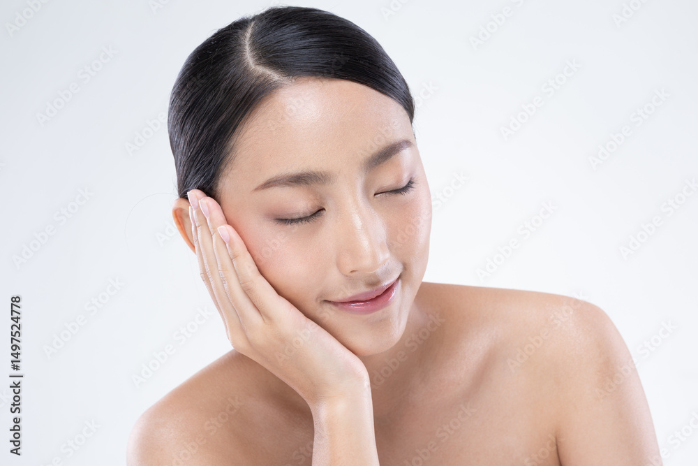 Asian serene woman with flawless skin and natural makeup gently touching her face, showcasing skincare or beauty concept against clean white background Asian serene woman with flawless skin and natural makeup gently touching her face, showcasing skincare or beauty concept against clean white background
