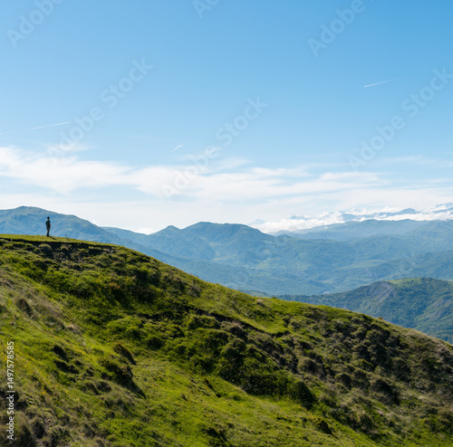 Solitary man standing on green hilltop in Ismayilli, Azerbaijan looking at the Greater Caucasus Mountains. photo