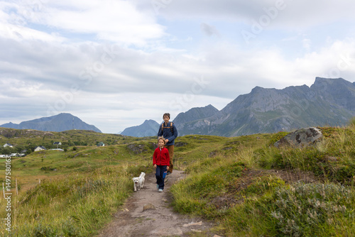 Happy children with parents and dog, european family, hiking the Kvalvika trail on hill at Kvalvika beach, Norway