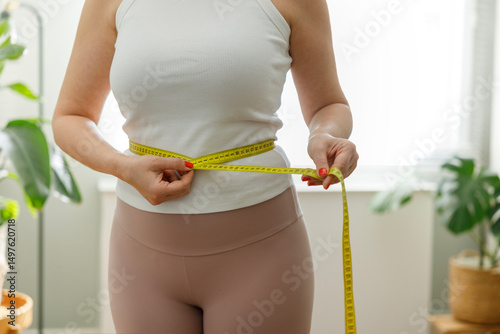 Young woman measuring her waistline