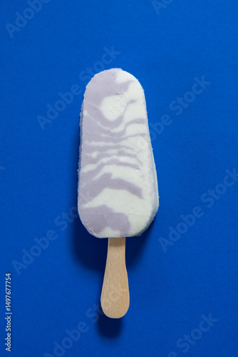 Vertical flat lay view of blueberry Greek yogurt frozen bar on bright blue background