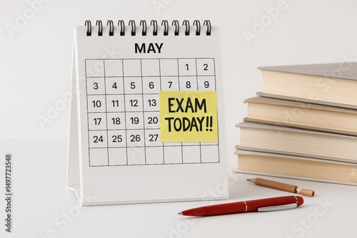 Calendar on May with a sticky note marked Exam Today next to a stack of books and a red pen. Educational concept about exam day, study time, and academic schedule reminder