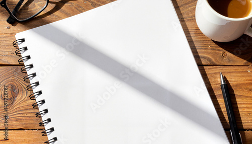Blank notebook on wooden table with coffee cup and pen