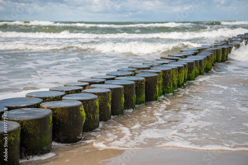 Fototapeta Naklejka Na Ścianę i Meble -  Wooden breakwater in the Baltic sea, Germany. Seascape with waves and sand.