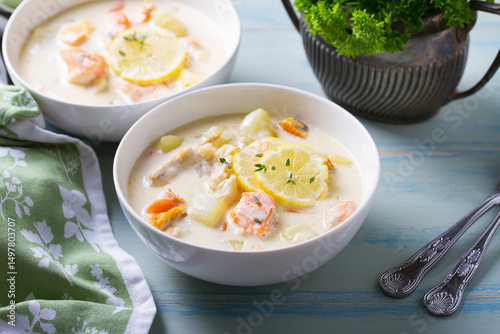 Fish and shrimp cream soup in white bowls on blue table