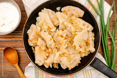 Dumplings,vareniki,varenyky,pyrohy with stewed cabbage,onion on pan.Traditional ukrainian popular national dish,cuisine served with sour cream on wooden board.