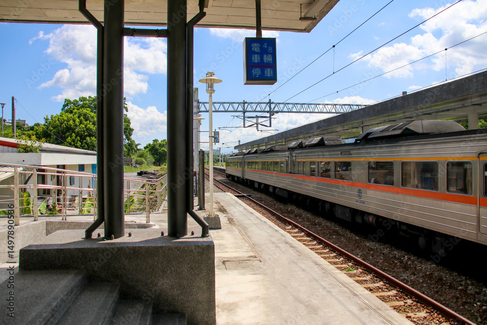 Fototapeta premium Taiwan May 21, 2024: A scenic view of a train at Fuli Station in Hualien, Taiwan, with clear sky and mountain background. Ideal for travel, transport, and rural tourism themes. Fuli Station