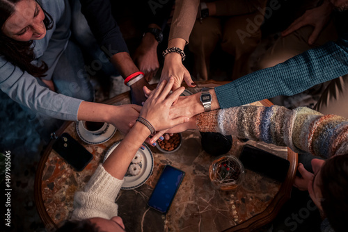 Diverse friends stacking hands in cozy cafe, teamwork and authentic unity