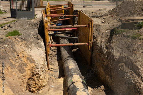 The excavated trench boasts a large pipe and various safety equipment used for construction and engineering purposes