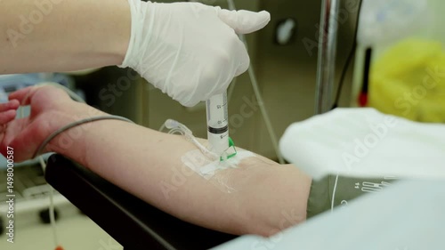 Healthcare worker wearing sterile gloves inserting intravenous catheter, delivering medication to patient's arm during medical treatment inside hospital room