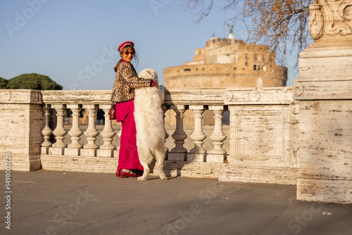Obraz na plátně A woman embraces her dog on a Roman bridge with Castel SantAngelo in the background
