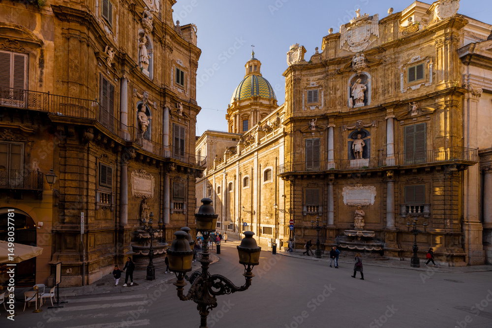 Fototapeta premium People stroll through Quattro Canti square in Palermo as golden light illuminates the baroque facades. This photo captures architectural elegance and the charm of urban exploration in Sicily