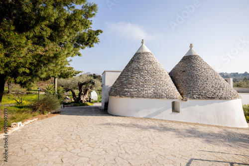 Quadro su tela Two traditional conical roofs of a whitewashed trullo house under a clear sky in